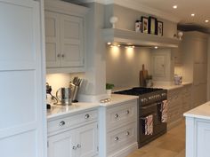 a large kitchen with white cabinets and stainless steel stove top oven in the center island