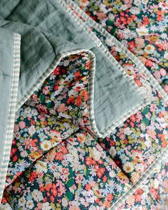 a close up of a flowered bed spread on top of a wooden headboard