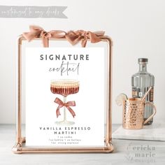 a sign that says signature cocktail with a pink bow on it and a bottle in the background