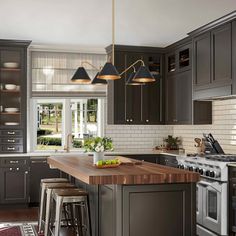 a kitchen with gray cabinets and wooden counter tops, an island in the middle is surrounded by stools