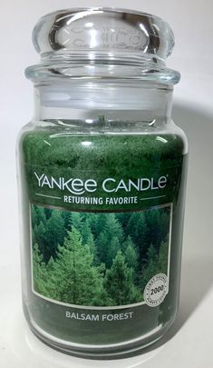 a jar filled with green trees on top of a white table