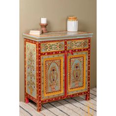 an ornate painted cabinet with candles on top