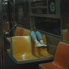 a person sitting on a subway train with their feet up in the seat and looking out the window