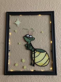 an insect is sitting on top of a glass frame with string lights around it and stars in the background