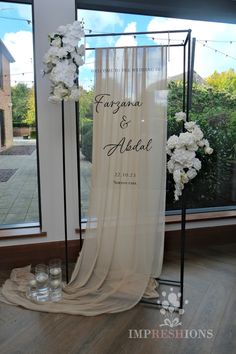 a wedding ceremony setup in front of a window with white flowers and candles on the floor