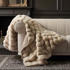 a couch with a blanket on it in front of a fireplace