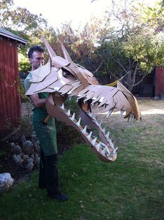 a man is holding up a cardboard dragon