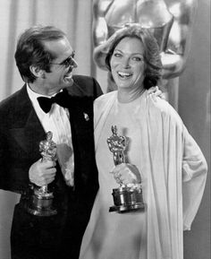 an old black and white photo of two people holding oscars