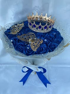 a blue and gold crown sitting on top of a white cloth covered box with ribbon