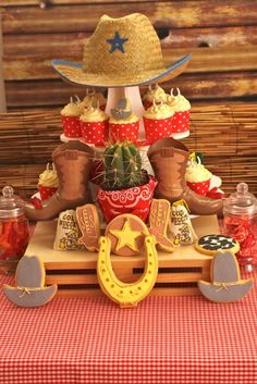 a table topped with lots of cupcakes and cowboy themed decorations on top of it