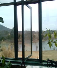 a table and chairs in front of large windows overlooking a body of water with trees on the other side