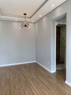 an empty room with hard wood flooring and a chandelier hanging from the ceiling