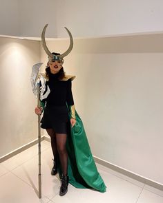 a woman dressed up as loki with horns on her head and holding a spear in one hand