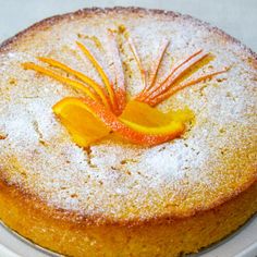 a cake on a plate with powdered sugar and orange peels in the middle