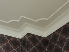 the corner of a room with decorative wallpaper and moldings on the ceiling,