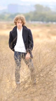 a young man is standing in the tall grass