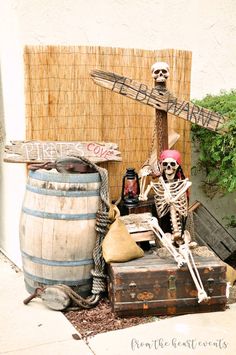 a skeleton sitting on top of a trunk next to a barrel