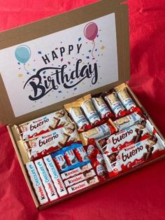 an open birthday box filled with candy and candies on a red cloth covered table