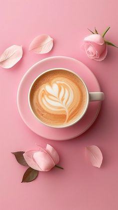 a cappuccino on a saucer surrounded by pink flowers and rose petals