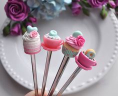 there are cupcakes with pink frosting on them in the shape of spoons