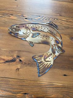 a metal fish sitting on top of a wooden floor