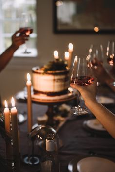 people holding wine glasses at a table with candles