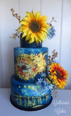 a three tiered blue cake with sunflowers on top