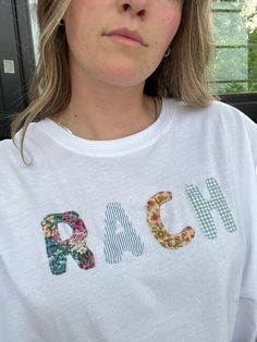 a woman wearing a white t - shirt with letters on it