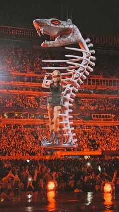 a woman standing on top of a giant skeleton in front of an audience at a concert