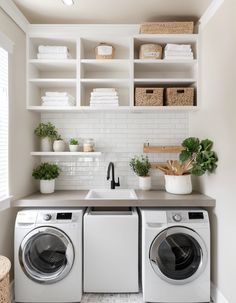 a washer and dryer in a white laundry room with open shelving on the wall