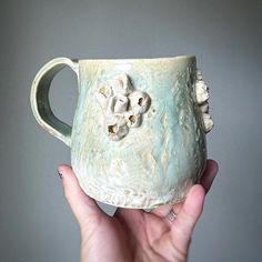 a hand holding a ceramic mug with flowers on it