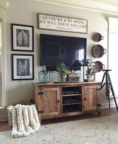 a living room with a large television and pictures on the wall above it's entertainment center