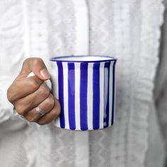 a woman holding a blue and white striped coffee cup