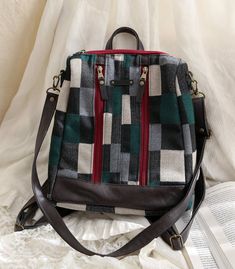 a handbag sitting on top of a bed next to an open book and white sheets