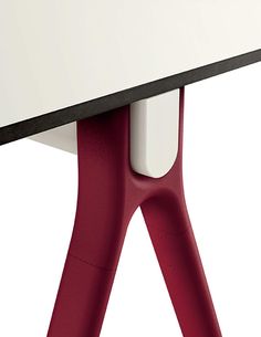 a white table with red legs and a black top is seen from the bottom view