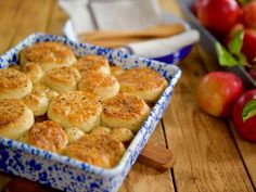 a blue and white dish filled with biscuits next to apples