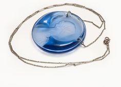 a blue object is sitting on a white surface next to a silver chain that has been attached to it