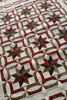 a quilt made with red, white and black stars on the front is shown in full view