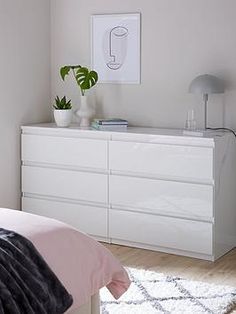 a bedroom with a white dresser and pink bedding on the floor next to it