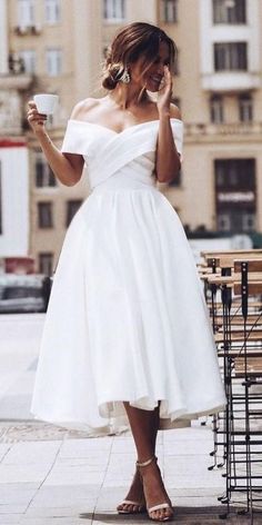 a woman in a white dress holding a coffee cup