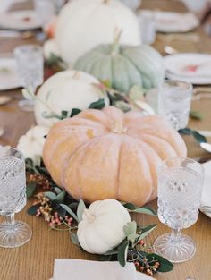 a table topped with lots of white pumpkins and greenery