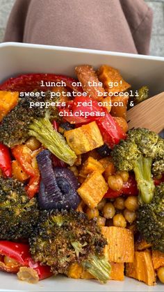 a white bowl filled with broccoli, carrots and chickpeas on top of a table