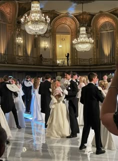 a large group of people in formal wear standing around each other on a dance floor