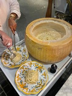 a person is preparing food in a large bowl on a table with plates and bowls