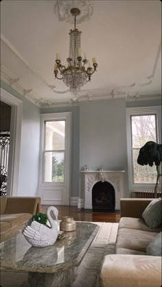 a living room filled with furniture and a chandelier hanging from the ceiling over a fire place