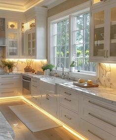 a kitchen with white cabinets and marble counter tops, along with lights on the windows