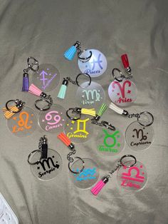 twelve acrylic keychains with zodiac signs on them, all in different colors