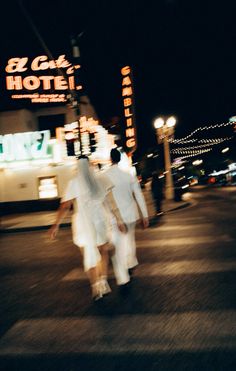 blurry photograph of people walking down the street in front of a hotel at night