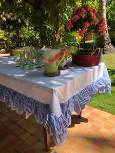 the table is set with dishes and glasses for guests to enjoy in the shade under the tree