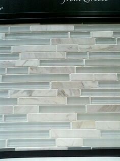 a white marble tile backsplash with black trim